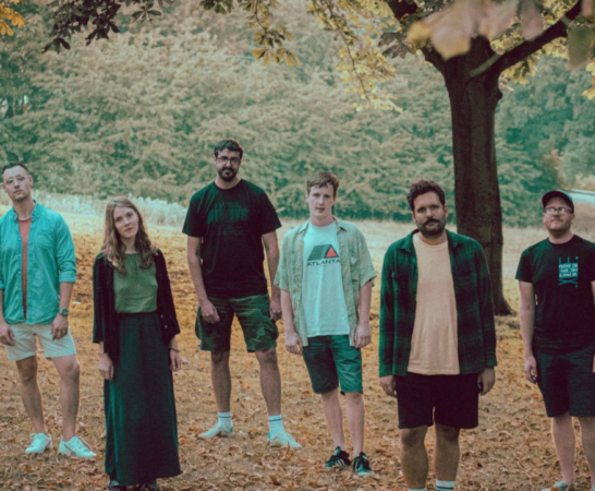 6 piece UK rock band Lakes stand together looking solemn